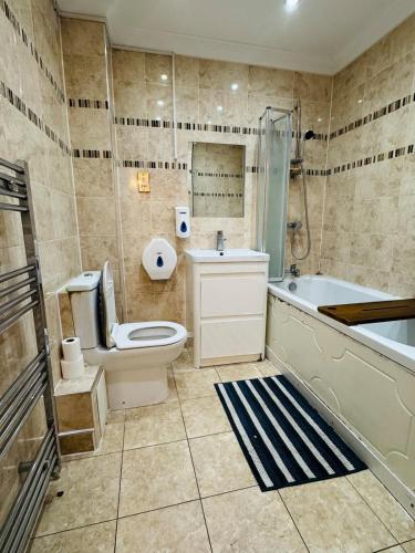 a bathroom with a toilet and a tub and a sink at Charming 2 Bedroom Flat with Urban Views in Romford