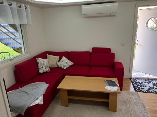 a red couch in a living room with a table at Gäst lägenhet i centrala Falkenberg botten plan utmärkt för äldre folk in Falkenberg
