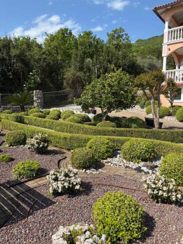 a garden with bushes and flowers in front of a building at Bed and Breakfast Villa Iris in Mošćenička Draga