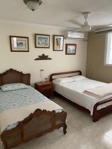 a bedroom with two beds and a table and pictures on the wall at Casa Estela in Cartagena de Indias