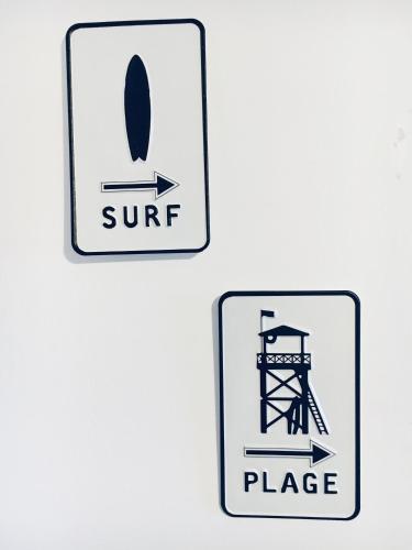 two signs on a wall with a surf and a place at Magnifique petit cocon bord de mer in Le Pradet