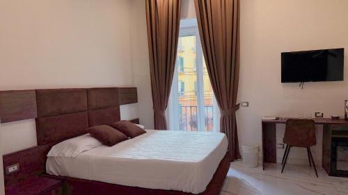 a bedroom with a bed and a desk and a television at AuRoom in Naples