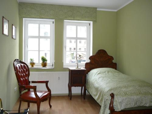 a bedroom with a bed and a chair and two windows at Schlafen in Weimar in Weimar