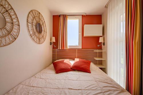 une chambre avec un lit avec deux oreillers rouges dans l'établissement Résidence le Village de Cap Esterel - maeva Home - Appartement 2 pièces 5 personnes - Prestige MAE-9071, à Saint-Raphaël