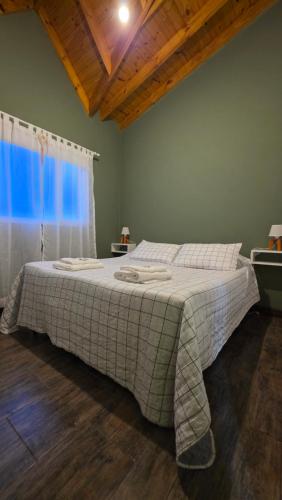 a large bed in a bedroom with a window at Posada Alma del Cerro in El Calafate