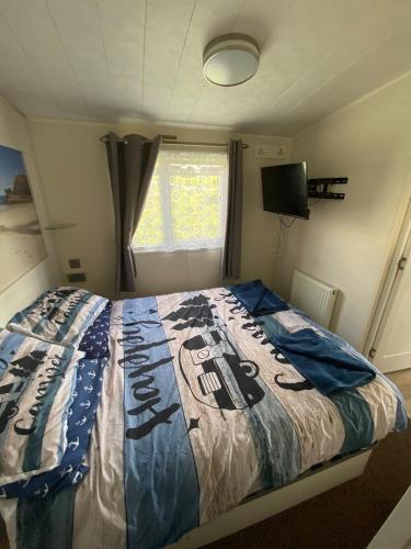 a bedroom with a bed with a quilt on it at Beautiful beach themed static caravan in Hastings