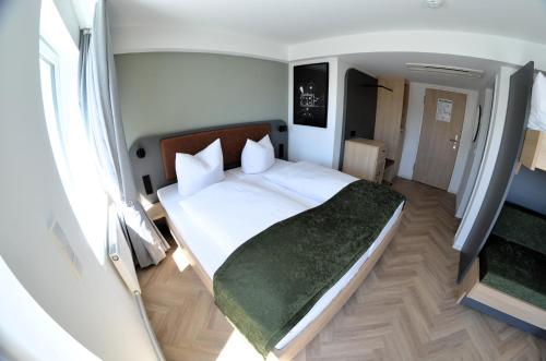a bedroom with a white bed with a green blanket at Cinema City Hotel Europaplatz Karlsruhe - Brand New Boutique Hotel 2025 - in Karlsruhe