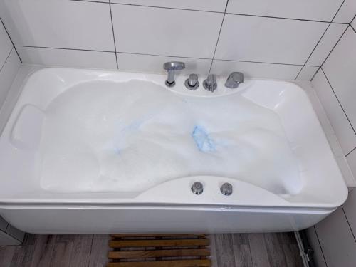 une baignoire blanche avec des débris bleus dedans dans l'établissement Bonaparte Spa & Terrace, Évry-Courcouronnes