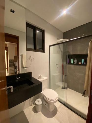 a bathroom with a toilet and a glass shower at Casa em condomínio Campina Grande in Campina Grande