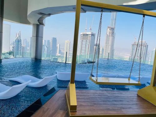 a swing in a pool with a view of the city at Luxury Seaview 2BR - Paramount Midtown - 6 Guests - 64F Pool Access & Burj View in Dubai