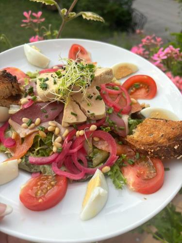 a white plate with a salad with tomatoes and other vegetables at Chambre double dans Auberge Alsacienne in Scherwiller