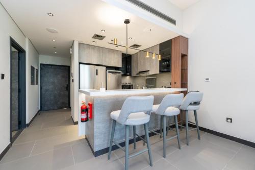 a kitchen with a bar with white stools at Brand New Luxury One Bedroom in Dubai