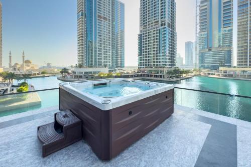 a hot tub on a balcony with a view of a city at Brand New Luxury One Bedroom in Dubai