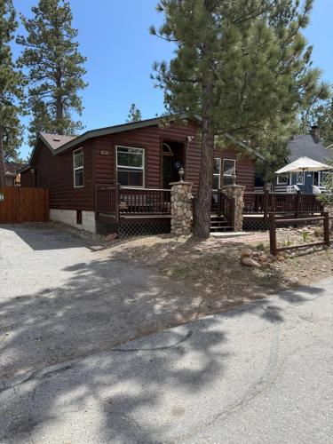 a log cabin with a tree in front of it at Whispering Pines - Big Bear Lake in Big Bear Lake