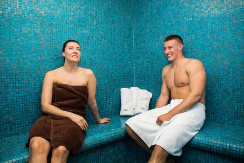 Ein Mann und eine Frau auf einer Couch in der Unterkunft Hotel Delfin Spa&wellness in Dąbki