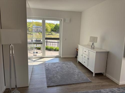 a white room with a dresser and a large window at V Gartenpalais Wohnung 1 in Norderney