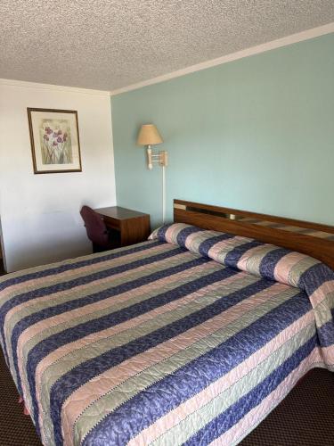 a bed in a hotel room with a striped bedspread at Royal Inn in Oklahoma City