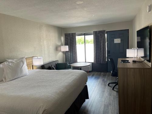a hotel room with a bed and a desk at Days Inn by Wyndham Branson Ozarks in Branson
