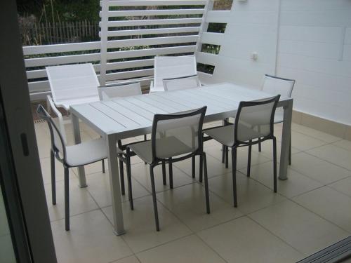 une table blanche et des chaises sur un balcon dans l'établissement Villa ACAPULCO - Port Nature VPN61 - Luxe - 4 personnes, au Cap d'Agde