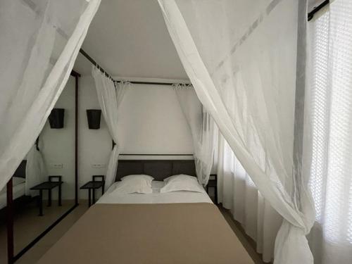 Ce lit se trouve dans un dortoir doté de rideaux blancs. dans l'établissement Villa ACAPULCO - Port Nature VPN61 - Luxe - 4 personnes, au Cap d'Agde