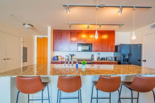 a kitchen with a large counter with chairs around it at Stunning 2BR DT HighRise, Gym, Pool, W-D, Parking, Golf in Phoenix
