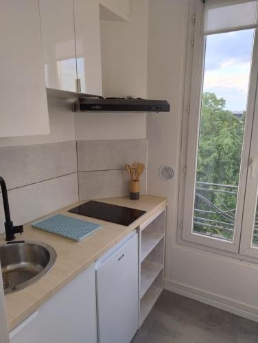 une cuisine blanche avec un évier et une fenêtre dans l'établissement Studio cosy - proche Metro13 G Péri, à Gennevilliers