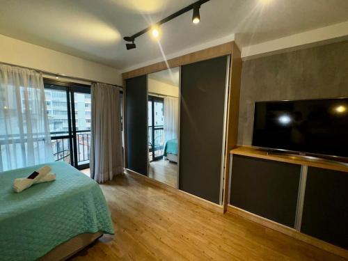 a bedroom with a bed and a flat screen tv at Studio I Bela Vista – 5min. do Metrô Liberdade in Sao Paulo