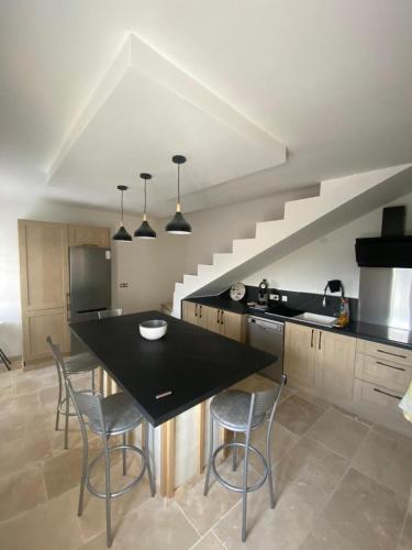 une cuisine avec un comptoir noir et quelques chaises dans l'établissement Maison de campagne, à Saint-Julien-de-Valgalgues