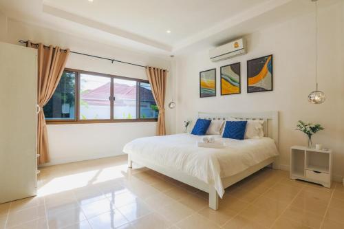 a bedroom with a bed and a large window at Wink Garden 3 Bedrooms Bangtao Beach Phuket in Ban Thalat Choeng Thale
