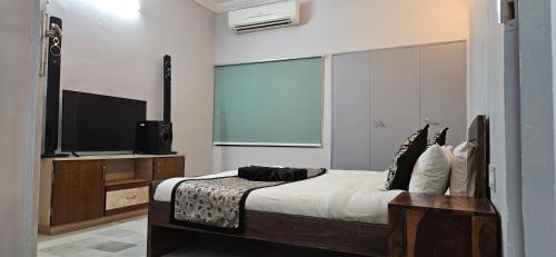 ein Schlafzimmer mit einem Bett und einem Flachbildfernseher in der Unterkunft Infinity Homestays 2 in Udaipur