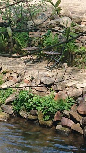 a bench sitting on top of rocks next to a river at Penzion Kůlna in Slatiňany