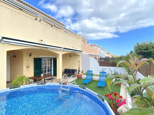 a backyard with a pool and chairs and a house at Porto de Mós Family House in Lagos