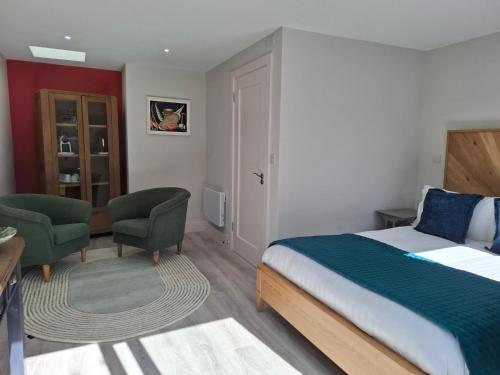 a bedroom with a bed and two green chairs at Granville House Apartments and Garden Suites in Ballyferriter