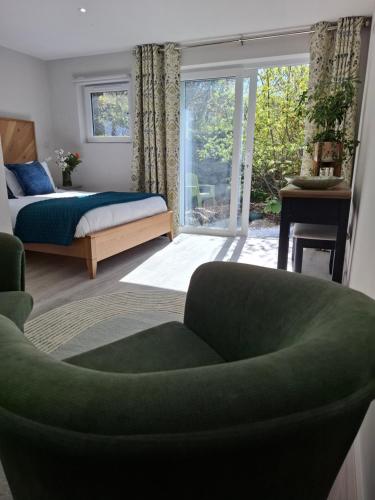 a bedroom with a green chair and a bed and a window at Granville House Apartments and Garden Suites in Ballyferriter