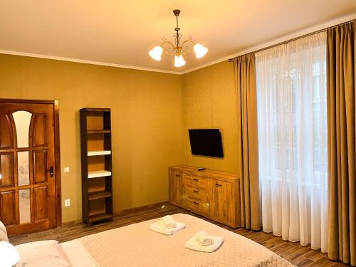 a bedroom with a bed and a tv and a window at Апарт-отель "ГАЛАГОВЪ" in Uzhhorod