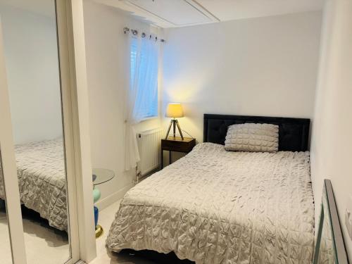 a white bedroom with a bed and a window at Modern, Tiny Home, Beach Retreat in Southerndown