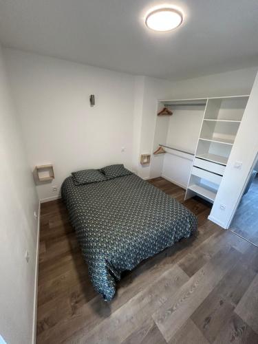 - une chambre avec un lit dans une pièce dotée d'étagères dans l'établissement Appartement T2 Saint Malo, Dinard, Dinan et Dol, à Miniac-Morvan