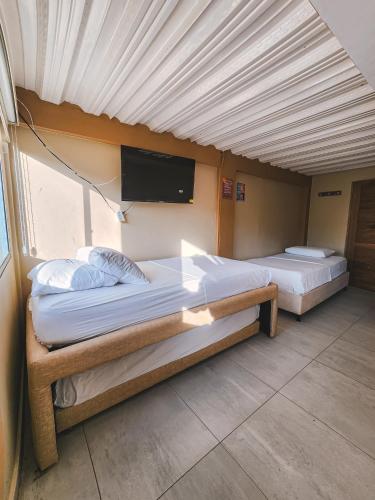 two beds in a room with a tv on the wall at Hotel y Cabañas Covemar in Coveñas