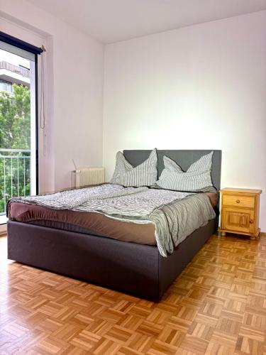 ein großes Bett in einem Zimmer mit Holzboden in der Unterkunft Balkonwohnung Graz neben Mol-Bio in Graz
