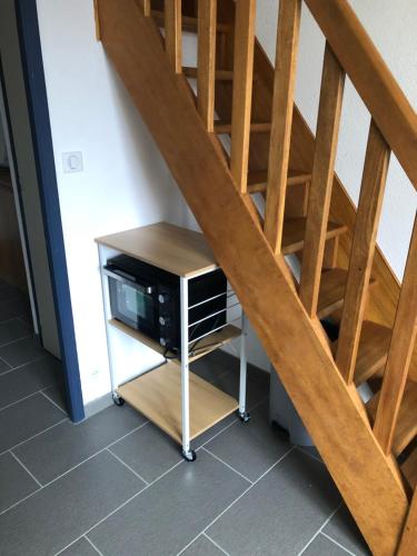 a desk with a microwave under a wooden staircase at Charmant duplex avec belle vue mer la plage à 100 m in Saint-Nic