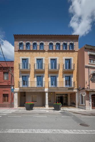 a large brick building with balconies on a street at Hotel La Grava in El Morell