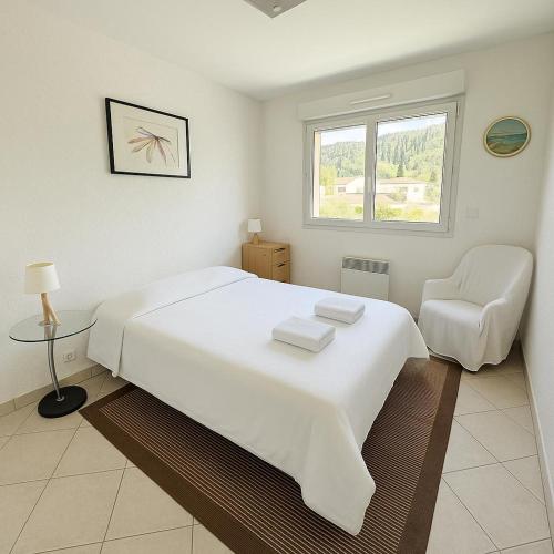 - une chambre blanche avec un grand lit blanc et une chaise dans l'établissement Magic Pool View, Rickeys, à Roquebrune-Cap-Martin