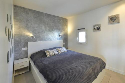 - une chambre avec un lit et un mur gris dans l'établissement Villa MORGANN - Port Nature VPN22 - Luxe - 2 personnes, au Cap d'Agde