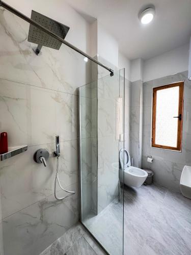 a bathroom with a glass shower and a toilet at Eden Hotel in Shëngjin