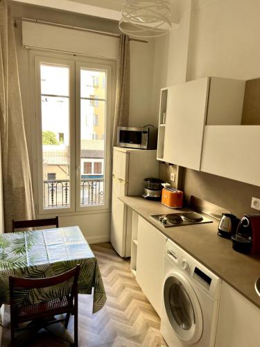 une cuisine avec une machine à laver et une table dans l'établissement Lumineux appartement dans le quartier des Fleurs, à Nice