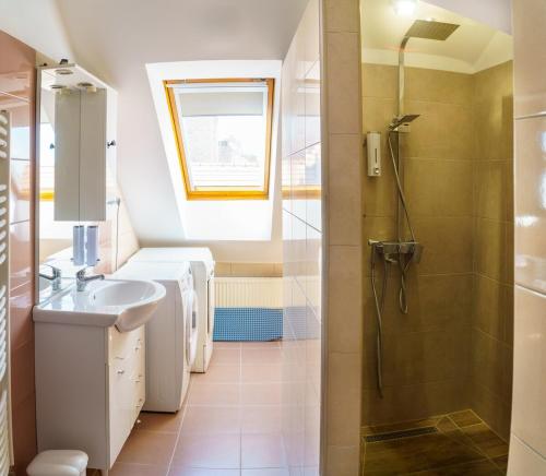Un baño con lavabo y ducha en KLEO Apartman, en Pécs