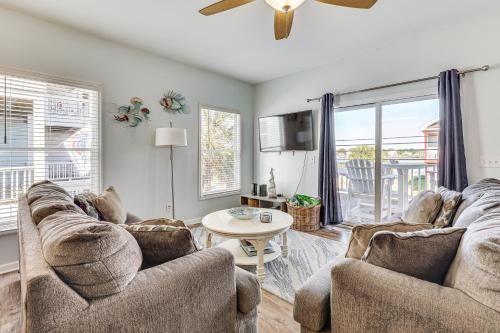 a living room with two couches and a table at Carolina Beach Condo with Deck Steps to Shore! in Carolina Beach