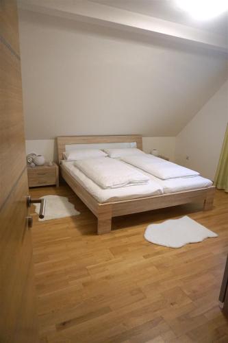 a bedroom with a bed with white sheets and wooden floors at Holiday home in a top location in Ferlach