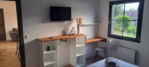 une pièce avec un bureau et une télévision sur un mur dans l'établissement la Maison d'à côté Chambre 3, à Cuise-la-Motte