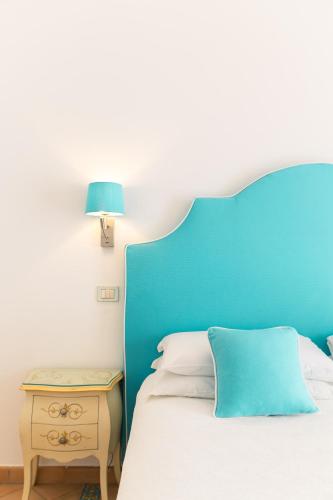 a bed with a blue headboard next to a table at Hotel Conca d'Oro in Positano